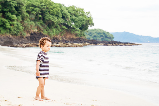 baby  walking along beach, smiling