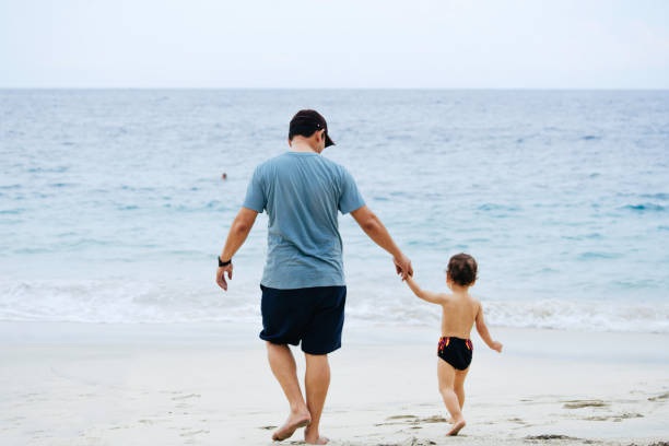 istock asian man teaching his baby walking on the beach 1471659780