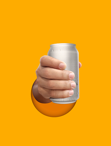 Man holding aluminum can with water droplets on yellow background