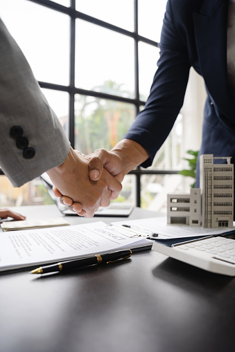 Close up shake hands, Considering buying a home, investing in real estate. Broker signs a sales agreement. agent, lease agreement, successful deal.