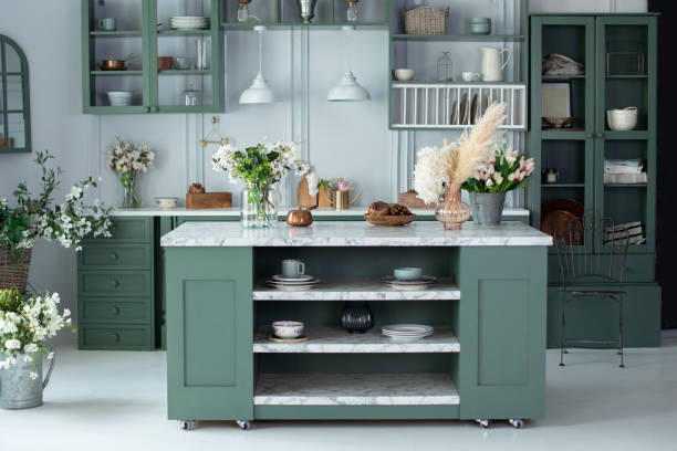istock Cozy home decor. kitchen island in dining room. Kitchen utensils, dishes and plate on table. Green kitchen interior with furniture. Stylish cuisine with flowers in vase. Wooden kitchen in summer decor 1471662929