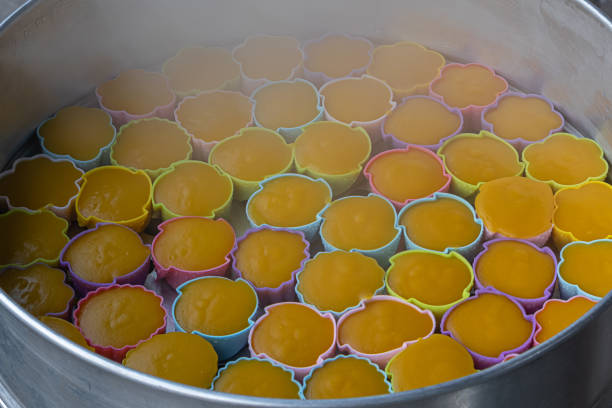 Thai Pumpkin Cake (Khanom Fak Thong) Pumpkin cake steaming in a steamer.