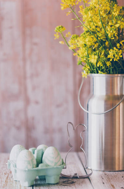 istock Cute still life of self painted mint green Easter eggs, an Easter bunny cookie cutter and a silver colored milk pot as a vase with a oilseed rape bouquet 1471664449