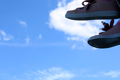 A pair of shoes hanging from a pole with the sky in the background.