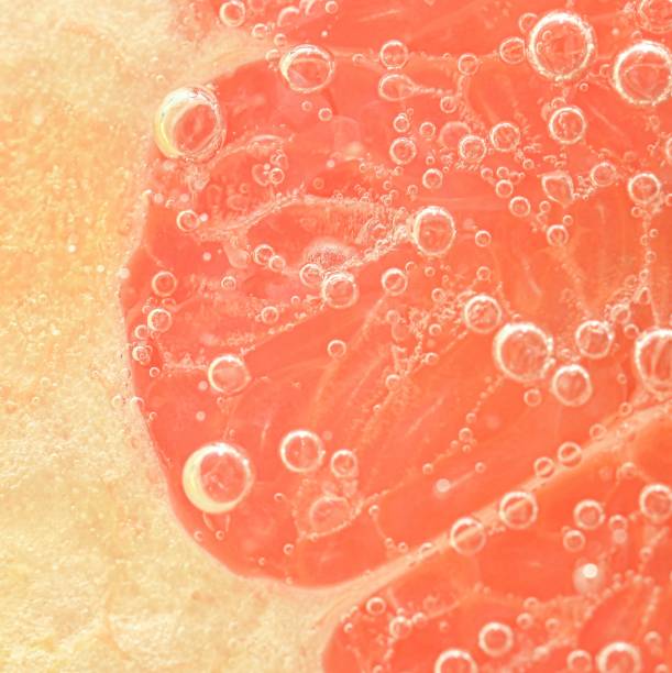 istock Slice of red grapefruit in water on white background. Grapefruit close-up in liquid with bubbles. Slice of red ripe grapefruit in water. Macro image of fruit in water 1471665207