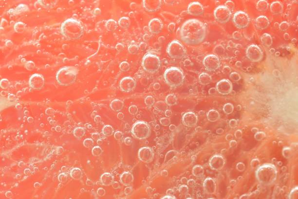 istock Close-up of a grapefruit slice in liquid with bubbles. Slice of red ripe grapefruit in water. Close-up of fresh grapefruit slice covered by bubbles 1471665249