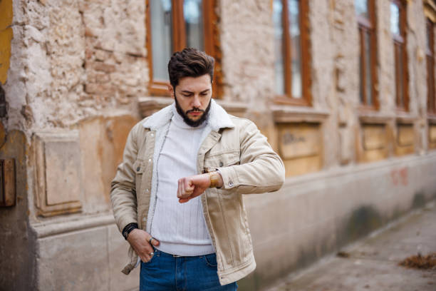 Handsome young man checking the time while walking in the city
