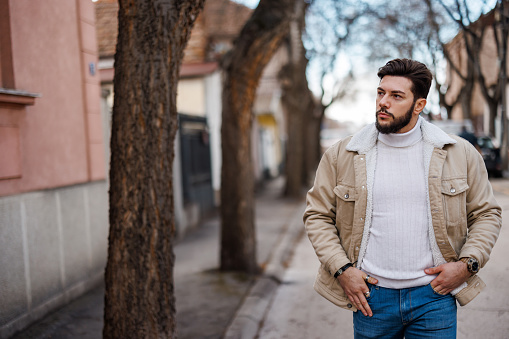 Handsome young man walking down the street on sunny day in the city