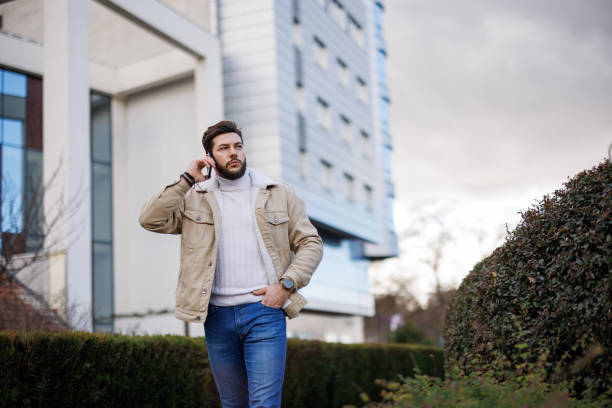 istock Young Caucasian man talking on smartphone while walking in the city 1471672755