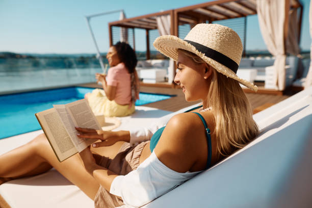 istock Young woman reading book while relaxing by the pool on summer vacation. 1471672812