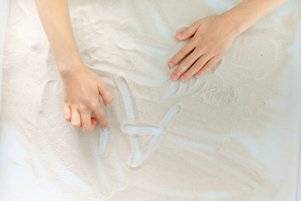 istock child's hands drawing letters in the sand 1471673250