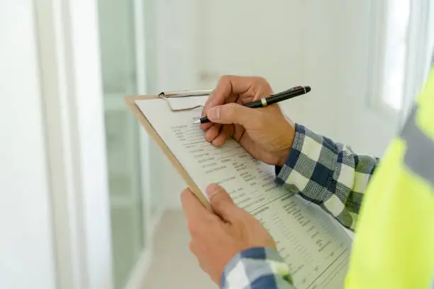 inspector or engineer is inspecting construction and quality assurance new house using a checklist. Engineers or architects or contactor work to build the house before handing it over to the homeowner