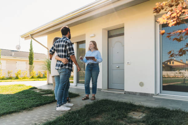 A real estate agent is showing an house to a couple A real estate agent is showing an house to a couple. They are next to the entrance of the home. sell home stock pictures, royalty-free photos & images