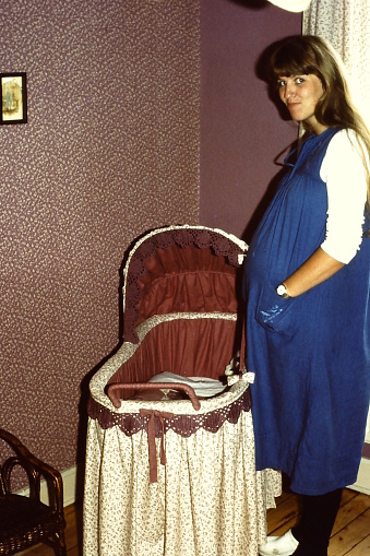 Young woman pregnant woman in the baby room, back in the seventies