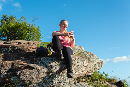 blonde woman using mobile on top of the mountain