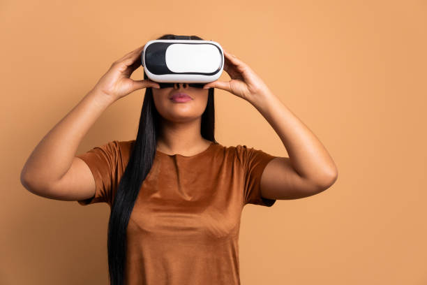 istock happy african american woman Using VR headset and gesturing in beige background. virtual reality, technology simulation concept. 1471678944