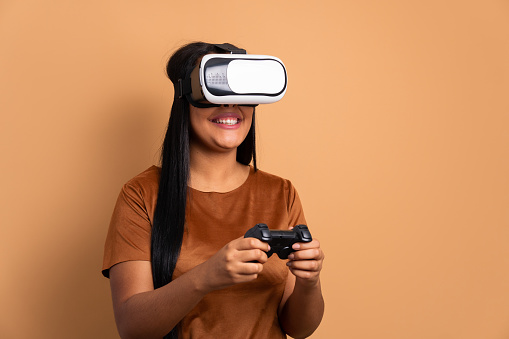 happy black woman playing videogame with VR headset in all beige colors. virtual reality, gaming, leisure concept.