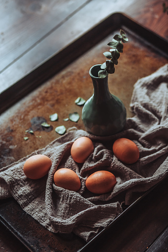ceramic vase, brown eggs and a grey cloth on a wooden table