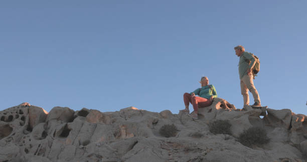 istock Mature couple ascend rock ridge, sunset 1471682567