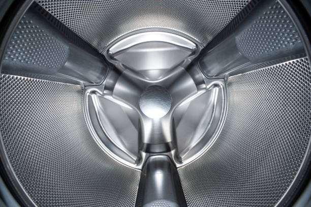 Washing machine or tumble drier metal perforated empty drum. Inside wide-angle view, no people