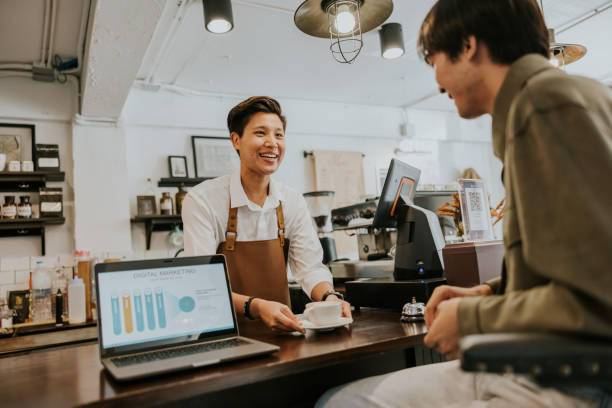 barista lgbtqia sonriente sirviendo capuchino caliente al cliente. - retail occupation customer advice fotografías e imágenes de stock