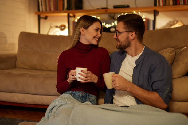 istock Young couple drinking tea while sitting in the living room at night 1471690851