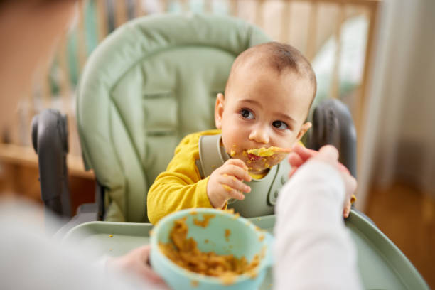 istock Mother spoon feeding her baby son at home 1471690895
