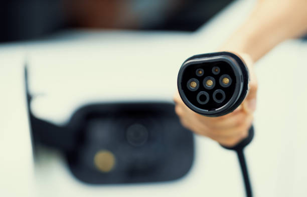 istock Progressive idea of focus hand pointing charging plug at camera, blur background 1471696881