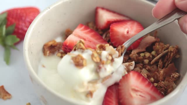 Homemade green buckwheat and nuts granola with coconut yogurt and strawberries in breakfast bowl.