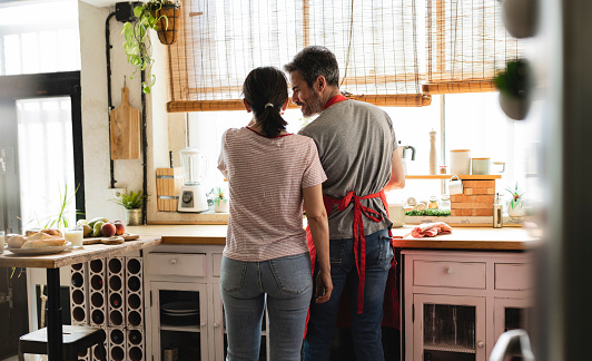mature couple preparing food in kitchen, rear view
