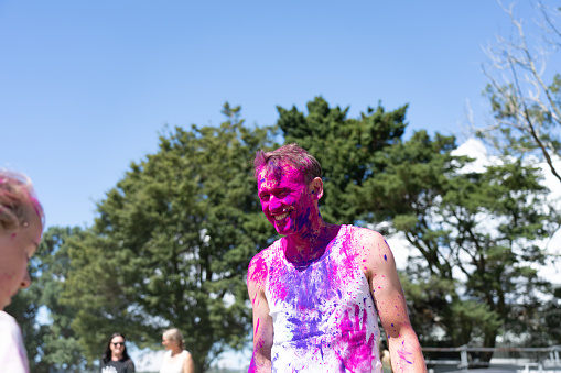 Tauranga New Zealand - March 4 2023; Man smiling and covered in bright powder and enjoying festivities at Holi Colour Splash at Memorial Park.