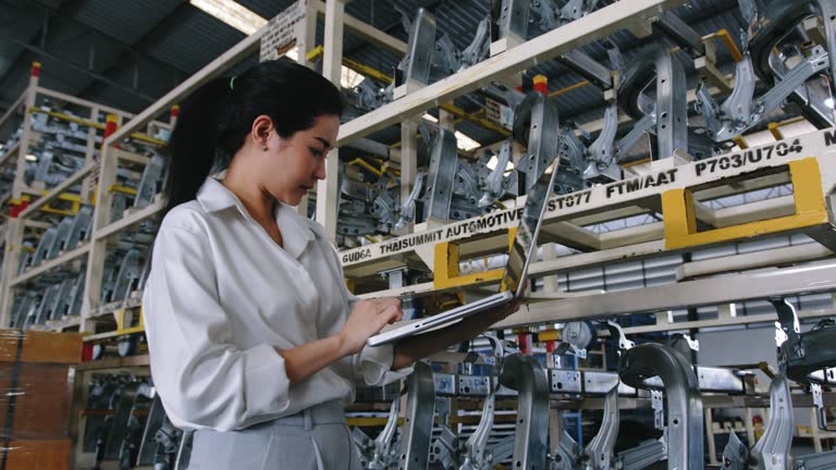 businesswoman using laptop computer checking Automobile part at warehouse