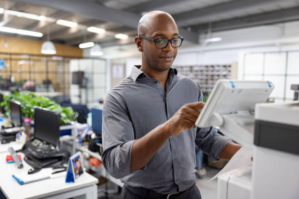 Business man working at the office and making a copy of a document Black business man working at the office and making a copy of a document computer printer stock pictures, royalty-free photos & images