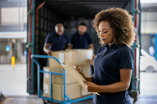 Woman supervising the shipping of cargo at a distribution warehouse