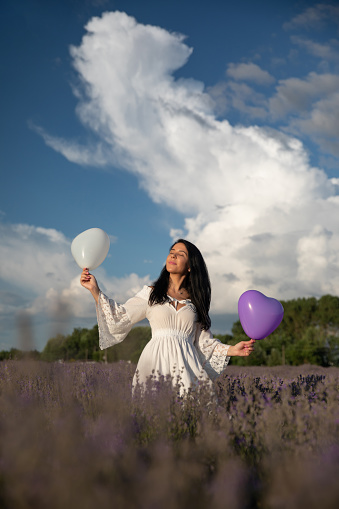 Young woman wandering in a lavender field, wearing a white dress.