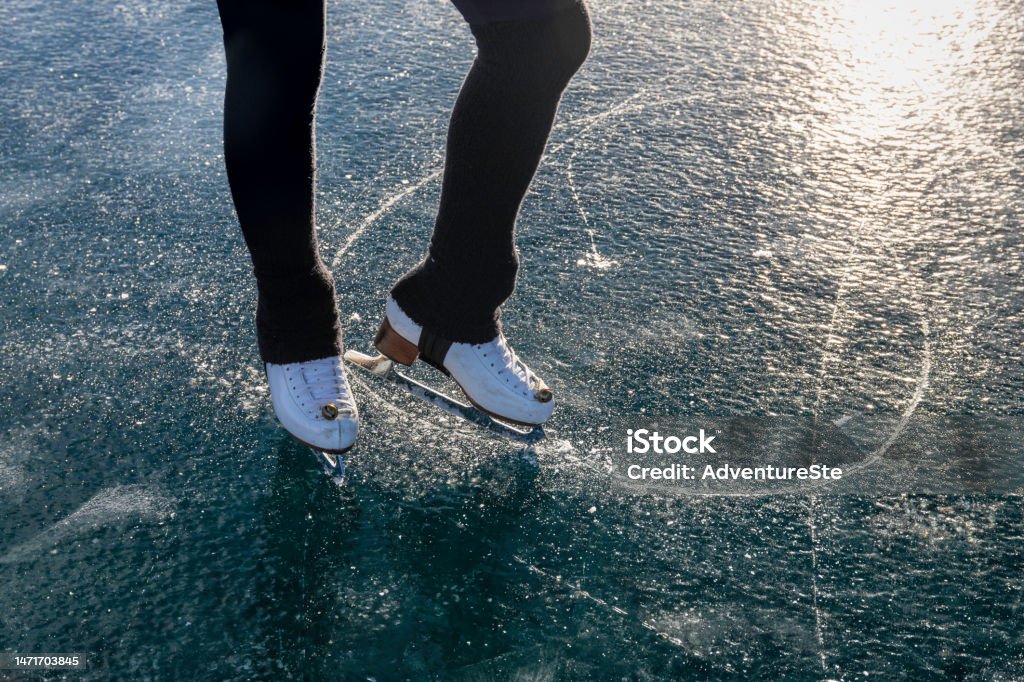 Girl with skates draws circles on the ice of Lake Silvaplana, Switzerland Low section of girl ready to skate on frozen Lake Silvaplana at sunset, Graubunden canton, Engadine, Switzerland Ice Stock Photo