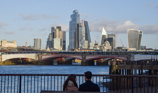 London, United Kingdom - January 30 2023: a couple enjoy the view of the City of London skyline, River Thames and Blackfriars Railway Bridge.