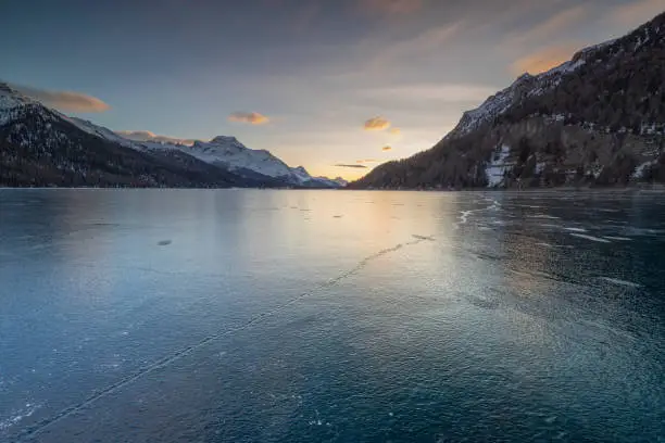 Snowcapped mountains reflected in the frozen water of Lake Silvaplana at dawn, Maloja, Engadine, Graubunden canton, Switzerland