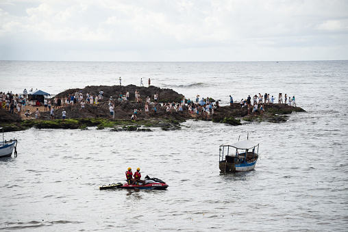 Salvador, Bahia, Brazil - February 02, 2023: Many people are on the rocks of Rio Vermelho beach offering gifts to Yemanja, in Salvador, Bahia.