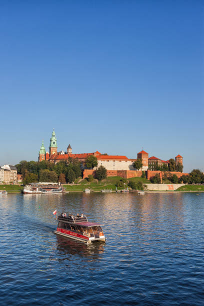 River Cruise Below Wawel Castle In Krakow Krakow, Poland - September 19, 2018 - The Wawel Castle and tour boat on Vistula River with tourists on sightseeing tour. wawel cathedral stock pictures, royalty-free photos & images