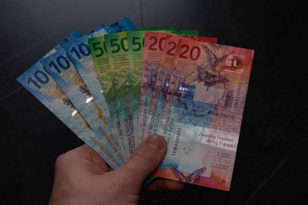 l’homme tient des billets de banque suisses à la main et compte ses revenus mensuels. - switzerland swiss currency chf euro symbol photos et images de collection