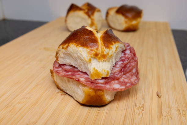 A man makes a salami sandwich with lye bread and butter.