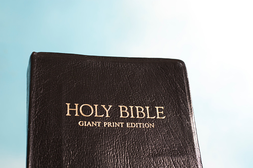 Closed Holy Bible against a blue sky.    Leather bound with gold lettering.  Giant print edition.