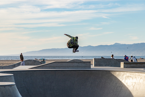 Los Angeles, United States - November 17, 2022: A picture of a skater doing a jump trick on the Venice Beach Skatepark.