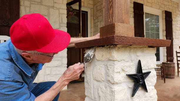 arbeiter oder heimwerker, der den säulenkappen der säulen auf der veranda des hauses den letzten schliff gibt. - baseball cap old red caucasian stock-fotos und bilder