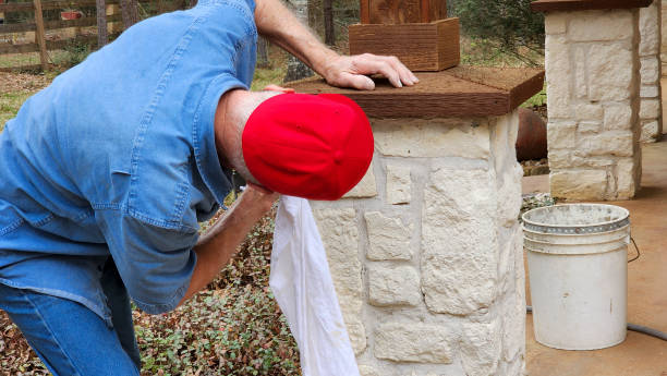 arbeiter oder heimwerker, der den säulenkappen der säulen auf der veranda des hauses den letzten schliff gibt. - baseball cap old red caucasian stock-fotos und bilder