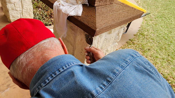 arbeiter oder heimwerker, der den säulenkappen der säulen auf der veranda des hauses den letzten schliff gibt. - baseball cap old red caucasian stock-fotos und bilder