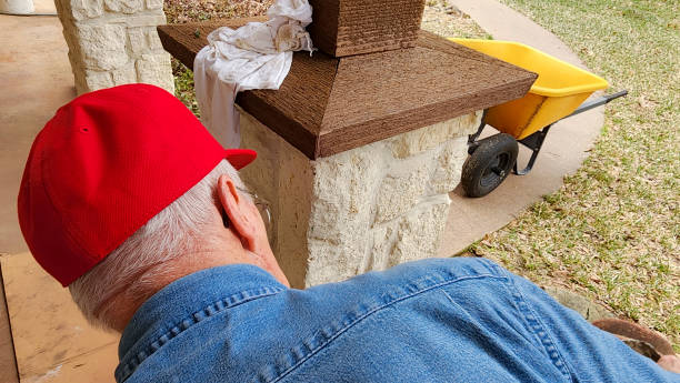 arbeiter oder heimwerker, der den säulenkappen der säulen auf der veranda des hauses den letzten schliff gibt. - baseball cap old red caucasian stock-fotos und bilder