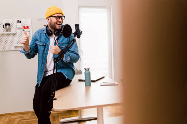 istock Young smiling man recording podcast and doing live streaming using microphone and headphones in recording studio 1471717848