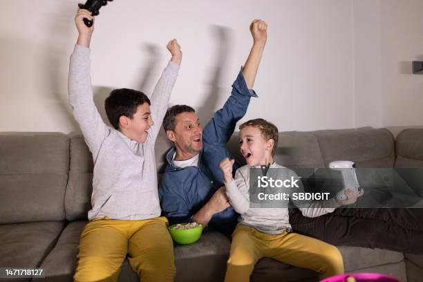 Father With Sons Celebrate Their Win At The Video Game On Playstation Stock Photo - Download Image Now